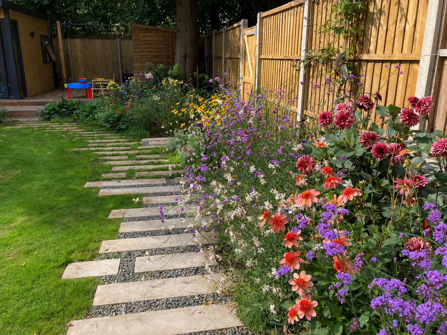 Colourful family garden planting in Hampstead, North London beside lawn and stepping stone path